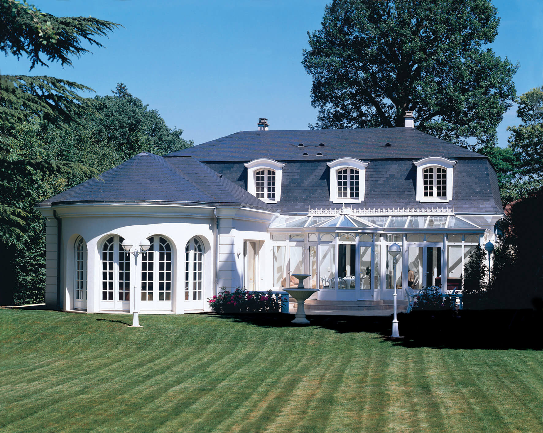 Maison vintage en pierre blanche avec toi bleu sombre, avec veranda et jardin